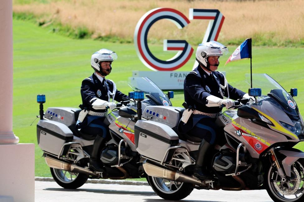 Des policiers français patrouillent à moto devant un panneau « G7 » à l’Hôtel Royal, à Évian, dans l’est de la France, le 15 juin 2026, à la veille du sommet du G7.