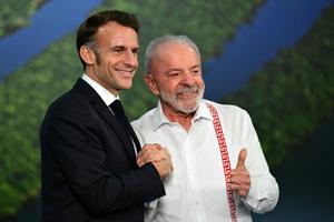 Le président français Emmanuel Macron et le président brésilien Luiz Inácio Lula da Silva saluent la foule après une rencontre bilatérale dans le cadre de la COP30, la conférence des Nations Unies sur le climat, à Belém, dans l'État du Pará, au Brésil, le 6 novembre 2025.