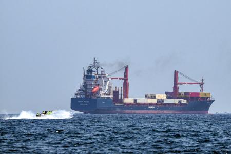 Un bateau s'approche du porte-conteneurs Marsa Victory, battant pavillon de Saint-Kitts-et-Nevis, alors qu'il navigue dans les eaux du détroit d'Ormuz, au large de Khasab,