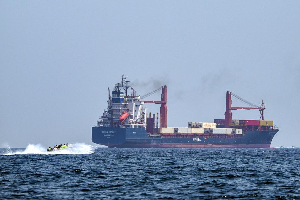 Un bateau s'approche du porte-conteneurs Marsa Victory, battant pavillon de Saint-Kitts-et-Nevis, alors qu'il navigue dans les eaux du détroit d'Ormuz, au large de Khasab,