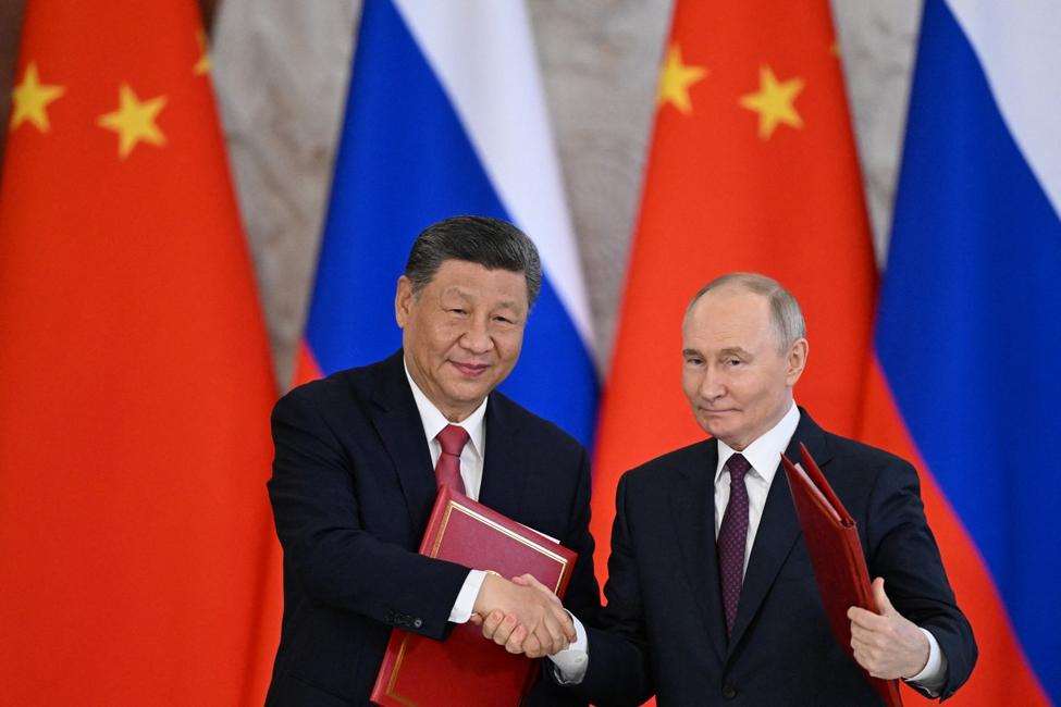 Le président russe Vladimir Poutine et son homologue chinois Xi Jinping échangent des documents lors d'une cérémonie de signature à l'issue de leurs entretiens au Kremlin à Moscou, le 8 mai 2025.