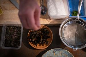 Le chef américain Josh Haner prépare un plat à base de condiments à base d'algues, entouré de bacs à algues, à Ballstad, près de Flakstad, dans les îles Lofoten, le 3 mars 2024.