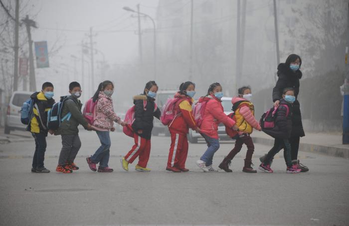 Des élèves traversent la rue en rang à Jinan, dans la province du Shandong (dans l'est de la Chine), au milieu d'une forte pollution atmosphérique.