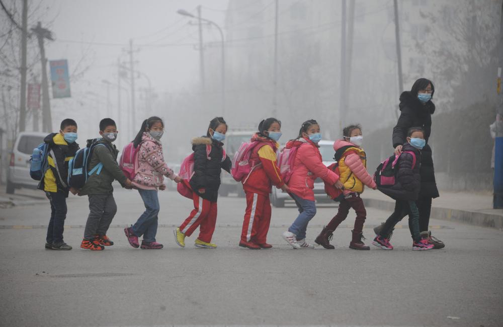 Des élèves traversent la rue en rang à Jinan, dans la province du Shandong (dans l'est de la Chine), au milieu d'une forte pollution atmosphérique.