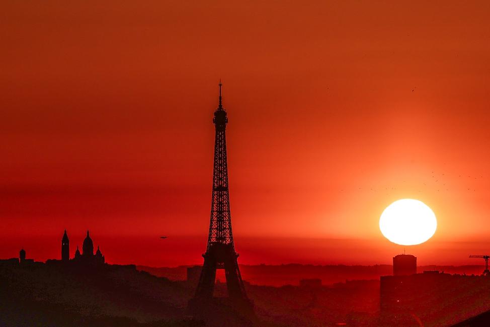 Le soleil se lève sur la tour Eiffel et la basilique du Sacré-Cœur, au sommet de la butte Montmartre à Paris, le 1er juillet 2025. La ville est en alerte rouge face à la canicule : le sommet de la tour Eiffel est fermé, la circulation polluante est interdite et des limitations de vitesse sont en vigueur.