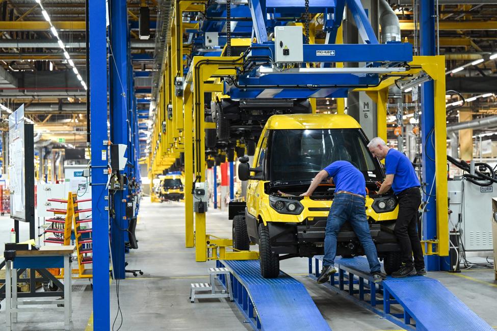 Des employés manipulent un véhicule électrique assemblé dans l'usine Neapco Europe de Düren, en Allemagne.