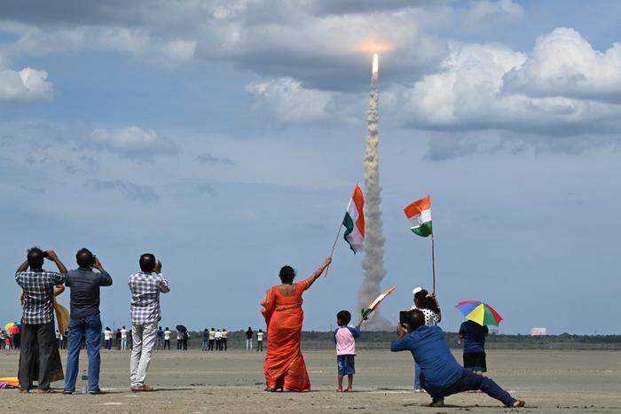 Des gens agitent des drapeaux indiens lors du décollage d'une fusée de l'Organisation indienne de recherche spatiale (ISRO) transportant le vaisseau spatial Chandrayaan-3 depuis le centre spatial Satish Dhawan à Sriharikota, le 14 juillet 2023.