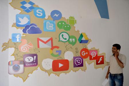 A Bangalore, un homme passe devant une fresque murale représentant divers réseaux sociaux, applications et services informatiques dont Gmail.