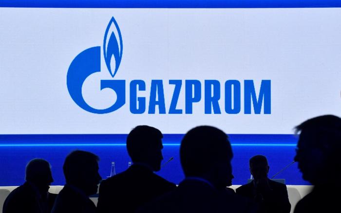 Des participants marchent devant un grand écran affichant le logo du géant russe de l'énergie Gazprom lors du Forum international du gaz de Saint-Pétersbourg (SPIGF) à Saint-Pétersbourg, le 15 septembre 2022.