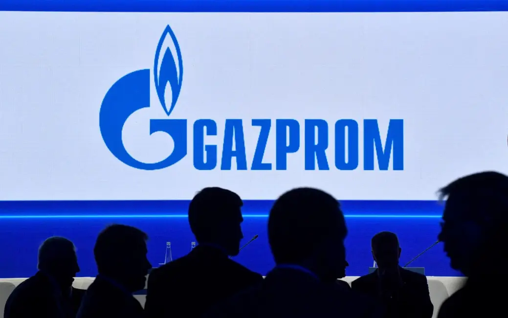 Des participants marchent devant un grand écran affichant le logo du géant russe de l'énergie Gazprom lors du Forum international du gaz de Saint-Pétersbourg (SPIGF) à Saint-Pétersbourg, le 15 septembre 2022.