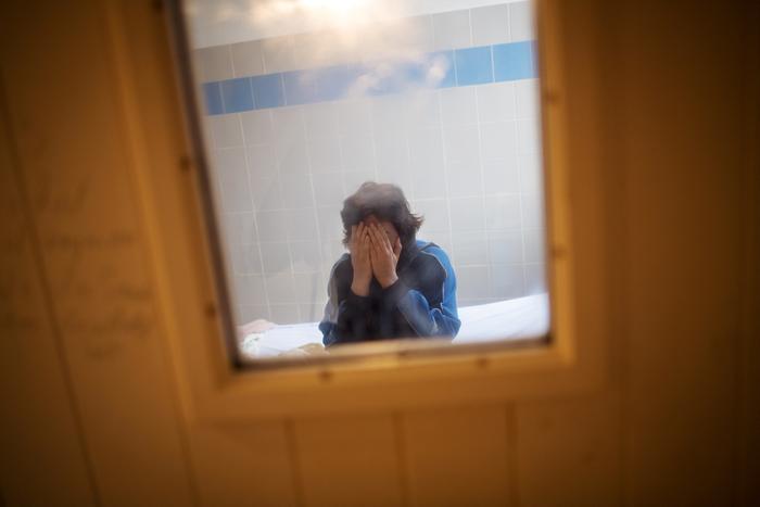 Un patient placé en chambre d'isolement se couvre le visage avec les mains, assis sur son lit à l'hôpital psychiatrique « EPS de Ville Évrard, Centre psychiatrique du Bois de Bondy », le 7 mai 2020, à Bondy. (Image d'illustration)