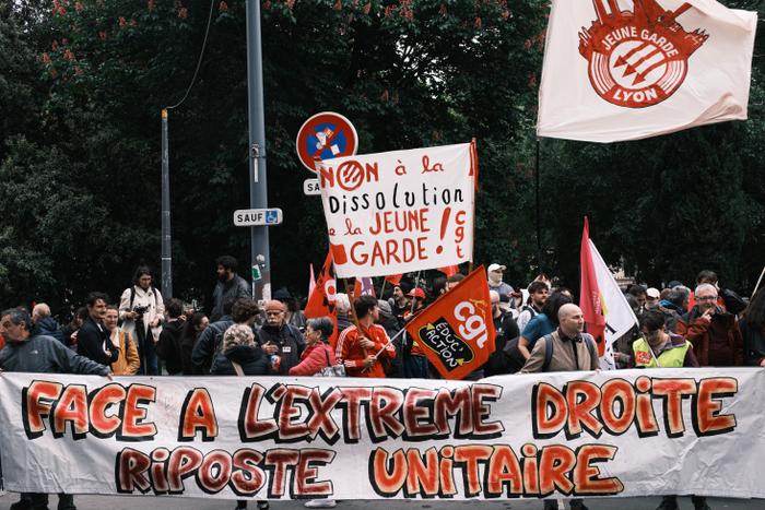 Des manifestants se tiennent derrière une banderole sur laquelle on peut lire : « Face à l’extrême droite, riposte unie », en soutien au groupe antifasciste La Jeune Garde, visé par une procédure de dissolution engagée par le ministre français de l’Intérieur, près de la préfecture du Rhône à Lyon, le 6 mai 2025. Le Conseil des ministres français a annoncé, le 12 juin 2025, la dissolution du mouvement antifasciste La Jeune Garde, ainsi que celle du groupe d’extrême droite Lyon Populaire.