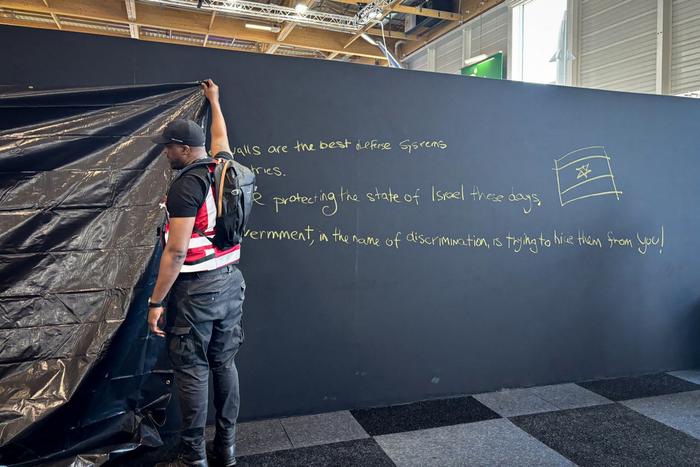 Un stand Israélien bloqué par des murs noirs installés dans la nuit et recouverts de tags pro-Israël.
