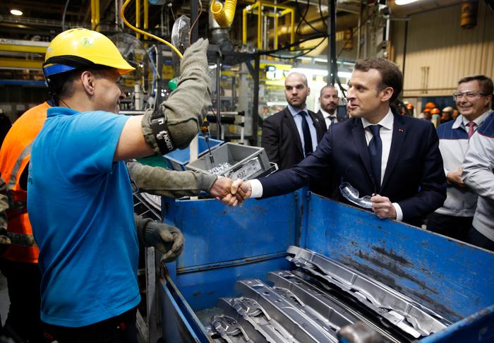 Le président français Emmanuel Macron serre la main d'un employé lors de sa visite de l'usine automobile Toyota à Onnaing, dans le nord de la France, le 22 janvier 2018.