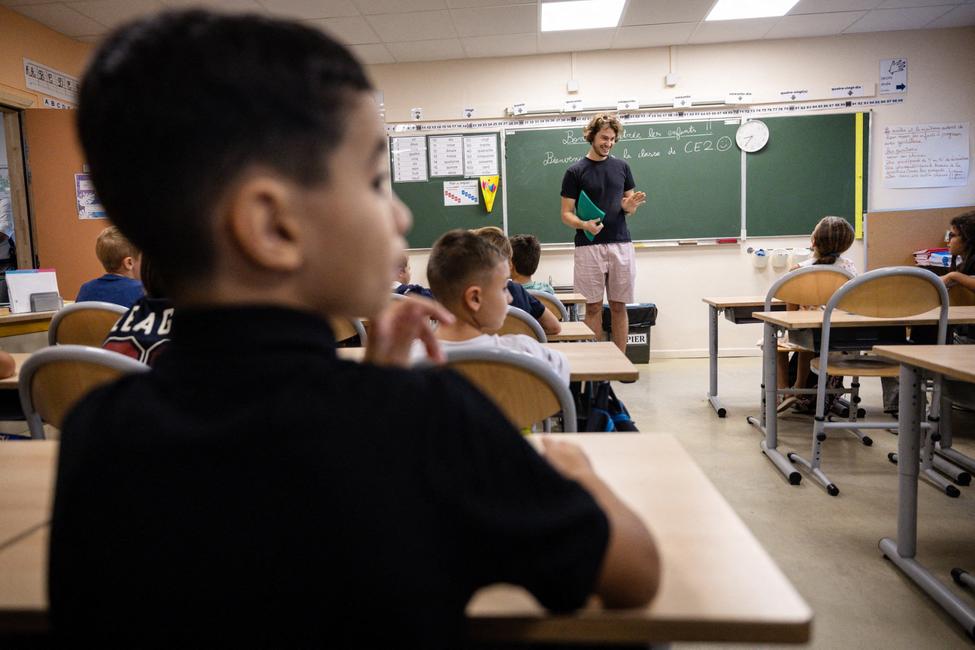 Des élèves sont accueillis par leur enseignant à leur entrée en classe, le jour de la rentrée scolaire, à l'école primaire Bonnevaine Zenatti de Marseille, dans le sud-est de la France, le 2 septembre 2024.