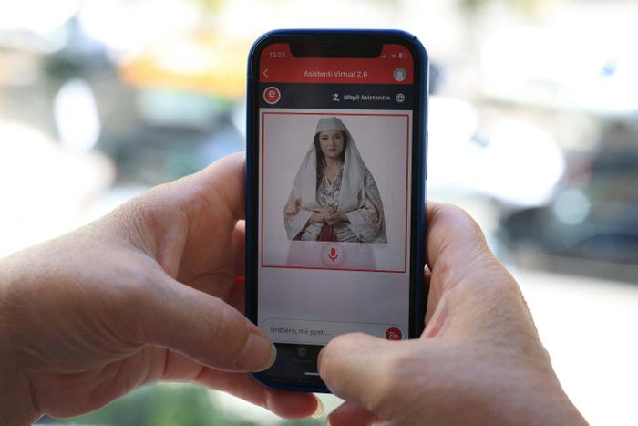 Une femme regarde son téléphone alors qu’elle utilise le portail gouvernemental albanais « E-Albania », désormais assisté par l’avatar « Diella », ministre virtuel de l’intelligence artificielle, à Tirana le 12 septembre 2025. Le Premier ministre albanais a annoncé le 11 septembre 2025 que l’avatar d’IA « Diella » deviendrait le premier ministre du cabinet « virtuellement créé », chargé des marchés publics dans le but de réduire la corruption.