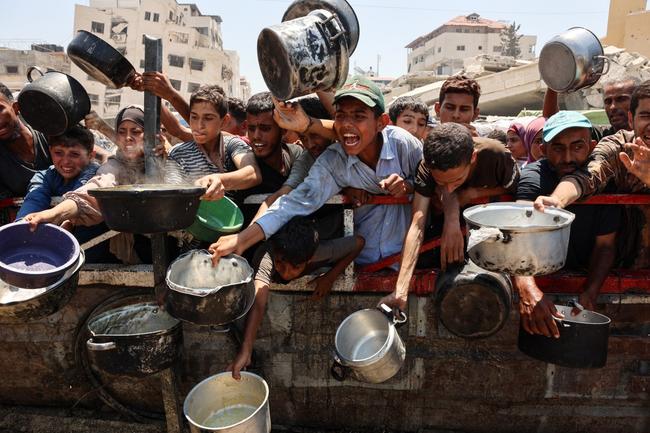 Des Palestiniens se rassemblent dans un point de distribution de soupe aux lentilles dans la ville de Gaza, le 27 juillet 2025.