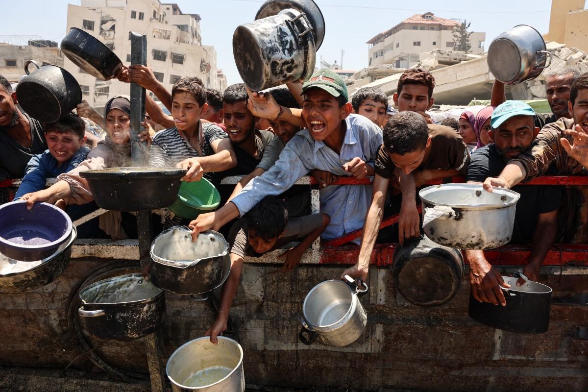 Des Palestiniens se rassemblent dans un point de distribution de soupe aux lentilles dans la ville de Gaza, le 27 juillet 2025.