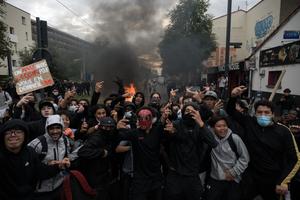 Des lycéens devant un feu qui brûle en arrière-plan, lors d'une manifestation près du lycée Déodat à Toulouse, dans le sud-ouest de la France, le 1er octobre 2026.