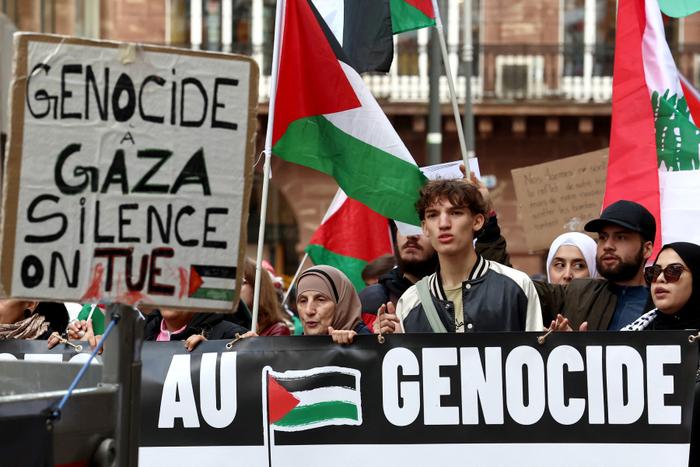 Des manifestants tiennent une pancarte sur laquelle on peut lire : « Génocide à Gaza, silence, nous tuons » lors d'une manifestation de soutien aux peuples palestinien et libanais à Strasbourg, le 5 octobre 2024.