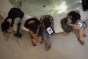 Des personnes utilisant leurs smartphones et tablettes dans un centre commercial de Bangkok.