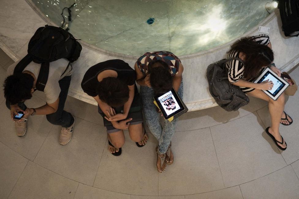 Des personnes utilisant leurs smartphones et tablettes dans un centre commercial de Bangkok.