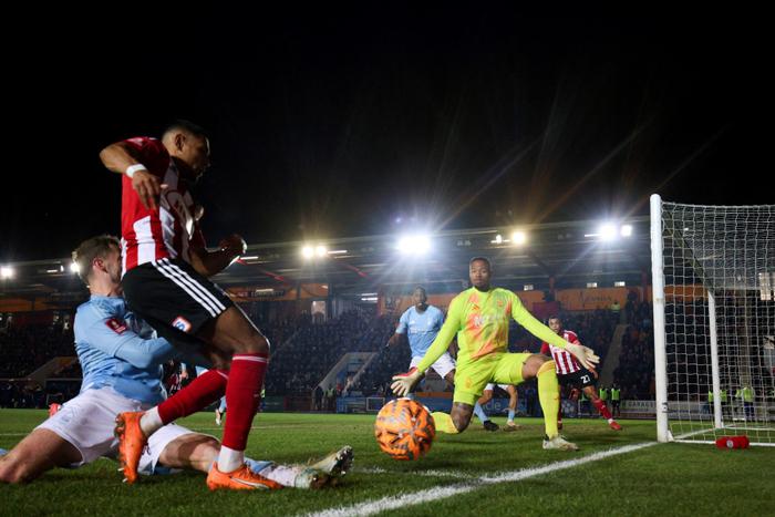 Le milieu de terrain anglais d'Exeter City Demetri Mitchell, devant le gardien brésilien de Nottingham Forest Carlos Miguel, lors du match entre Exeter City et Nottingham Forest à St James Park à Exeter, le 11 février 2025.