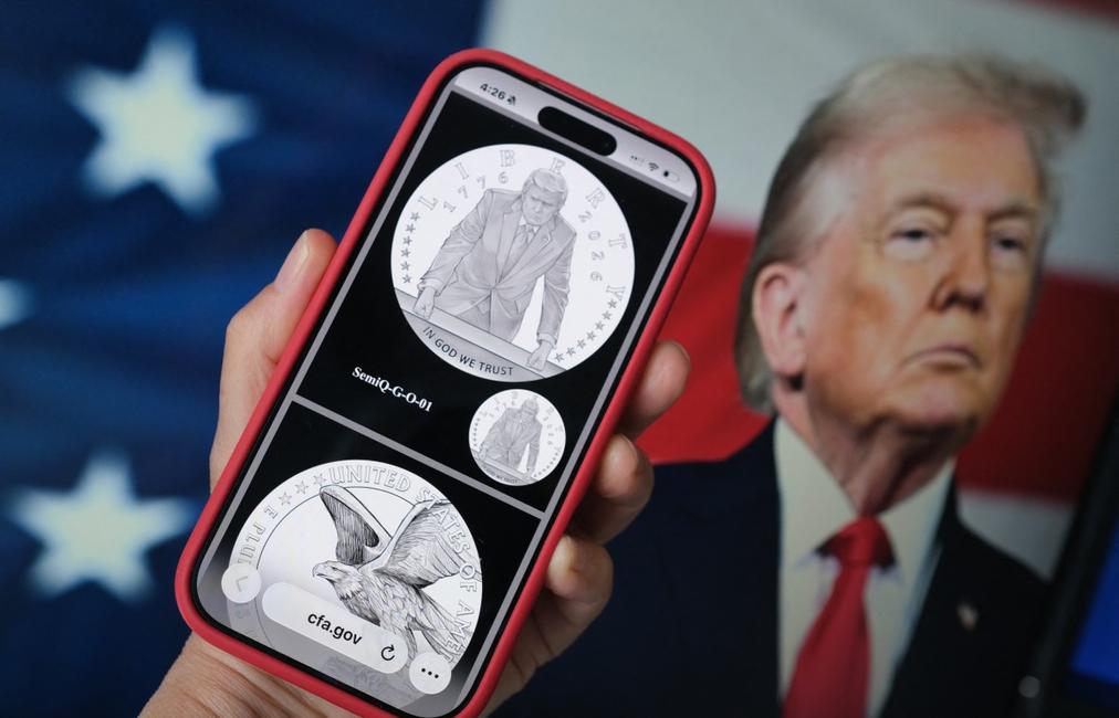 Le motif d'une pièce d'or commémorative marquant le 250e anniversaire des États-Unis — approuvé par la Commission des beaux-arts des États-Unis — devant une photo du président américain Donald Trump.