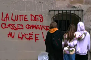 Des élèves passent devant un graffiti proclamant « la lutte des classes commence au lycée » près du lycée Sophie-Germain à Paris, le 9 octobre 2026, dans le cadre d'un mouvement de contestation national concernant les conditions d'apprentissage.