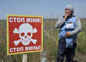 Un mineur de l'ONG HALO Trust fume pendant une pause de déminement dans un champ à l'extérieur du village de Snigurivka, dans la région de Mykolaiv, le 4 juin 2024