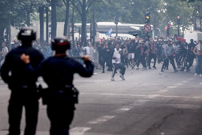 Des policiers affrontent la foule après le défilé du bus de l'équipe du PSG, près de l'avenue des Champs-Élysées à Paris, le 1er juin 2025