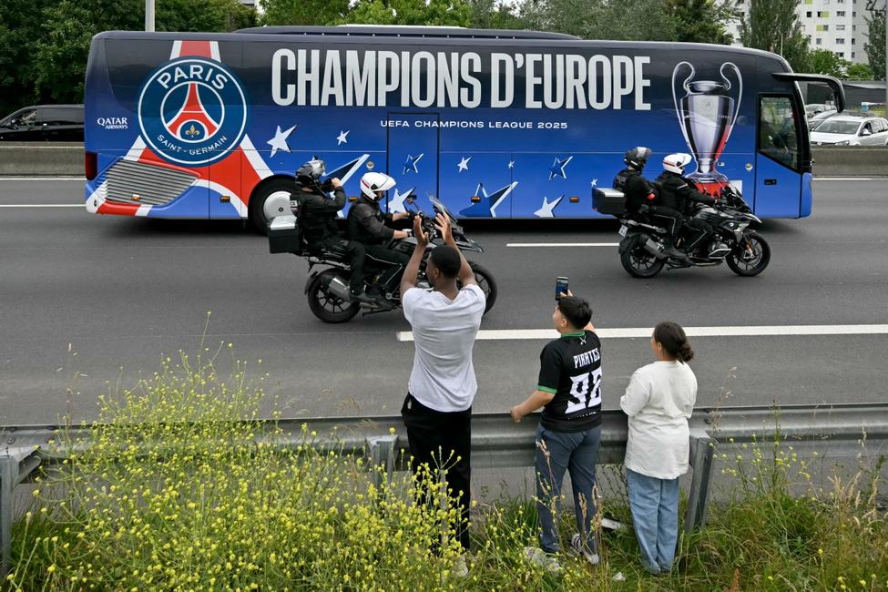 Les supporters du Paris Saint-Germain agitent des drapeaux tandis que le bus du PSG circule sur l'autoroute A1 à La Courneuve, en banlieue parisienne, le 1er juin 2025, au lendemain de la victoire du PSG en finale de la Ligue des champions de l'UEFA 2025 contre l'Inter Milan à Munich.