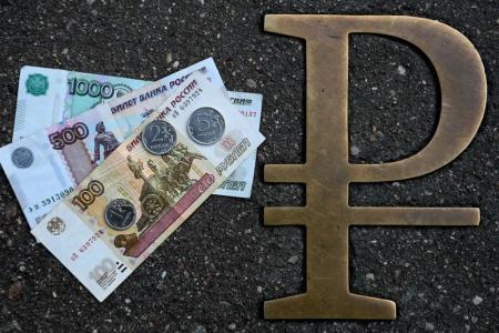 Cette photo prise le 13 août 2021 à Moscou montre des pièces et des billets en roubles russes à côté du signe du rouble russe.