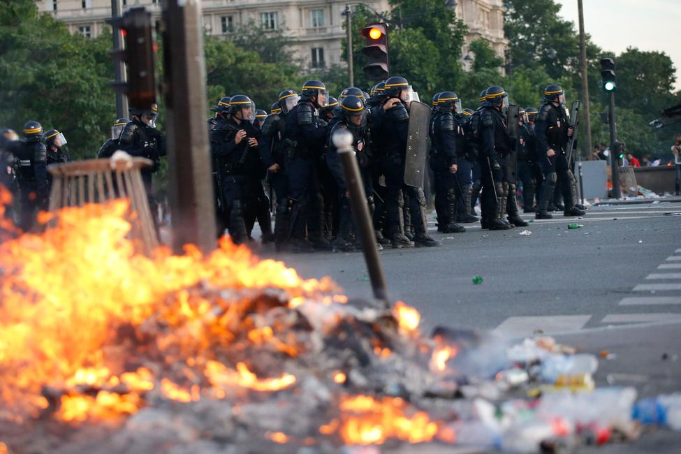 Des déchets brûlent près des forces de l'ordre lors d'affrontements près de la "fan zone" du champ de Mars à Paris pendant la finale France-Portugal de l'Euro 2016 le 10 Juillet 2016.