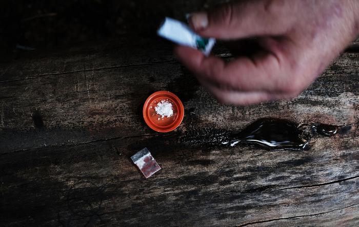 Un héroïnomane sans domicile fixe, mélange cocaïne et héroïne près d'un passage souterrain ferroviaire dans le quartier de Kensington à Philadelphie, devenu un haut lieu de la consommation d'héroïne, le 31 juillet 2017 à Philadelphie, en Pennsylvanie.