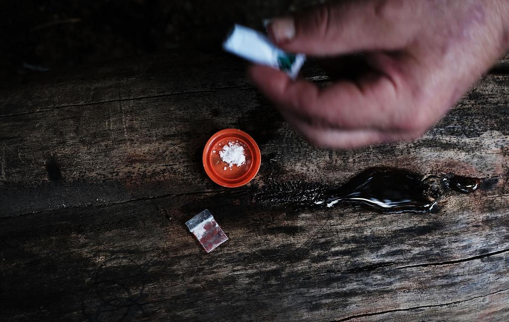 Un héroïnomane sans domicile fixe, mélange cocaïne et héroïne près d'un passage souterrain ferroviaire dans le quartier de Kensington à Philadelphie, devenu un haut lieu de la consommation d'héroïne, le 31 juillet 2017 à Philadelphie, en Pennsylvanie.