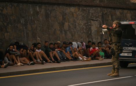 Un soldat espagnol utilise un mégaphone pour s'adresser à des migrants assis sur le trottoir avant de les escorter vers le Maroc, dans l'enclave espagnole de Ceuta, en Afrique du Nord, le 1er août 2026. Au moins 67 personnes ont trouvé la mort lors de la récente vague de traversées migratoires entre le Maroc et l'enclave espagnole de Ceuta, a annoncé ce jour-là le ministre espagnol de l'Intérieur. La plupart des quelque 60 000 migrants entrés à Ceuta en l'espace de quelques jours depuis le Maroc voisin sont déjà retournés au Maroc. (Image d'illustration)