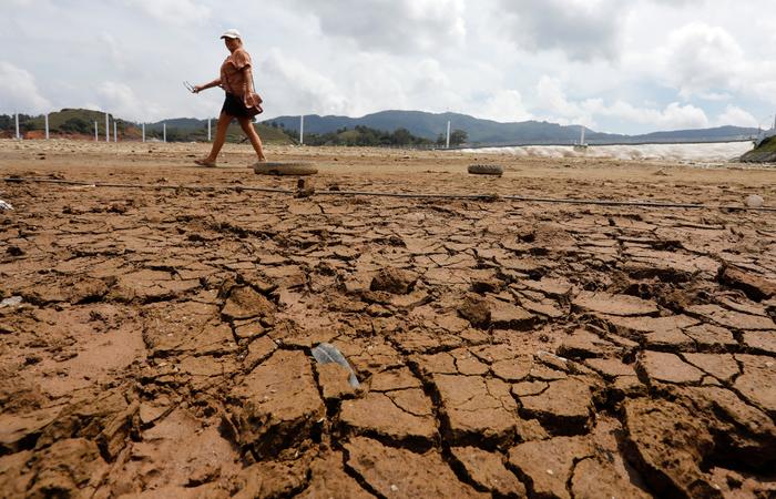 Lors du phénomène El Niño, une femme marche dans le réservoir asséché du Peñol de Guatapé, en Colombie, en mars 2024.