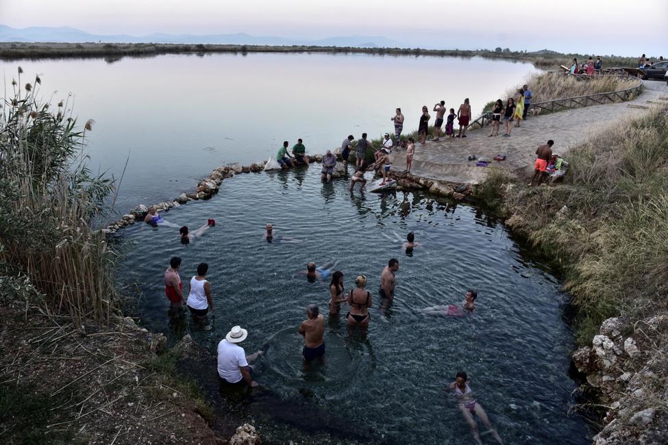 Des personnes profitent d'un bain dans les eaux froides d'une zone humide près de la plage d'Astros, dans le Péloponnèse, au sud de la Grèce.