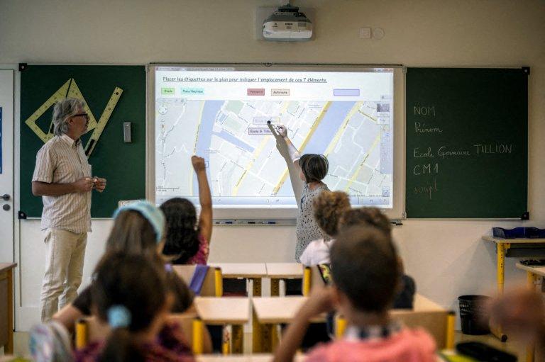 Dans une salle de classe de l'école primaire Germaine Tillion, à Lyon, pour la rentrée scolaire, une élève montre sur un tableau électronique interactif l'emplacement de son école sur une carte de la ville.