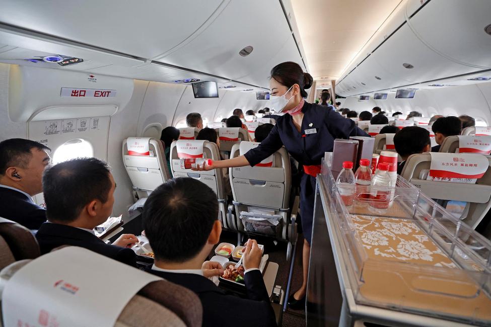 Une hôtesse de l'air distribue des bouteilles d'eau aux passagers lors du vol inaugural du C919, premier avion de ligne chinois de fabrication nationale.