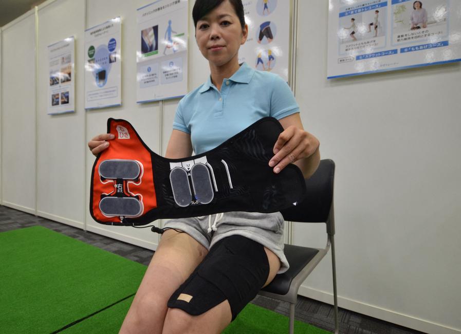 Une femme présente le « Hiza trainer » (un appareil de musculation pour les genoux) du géant japonais de l'électronique Panasonic, destiné aux personnes souffrant de douleurs aux genoux et aux seniors, à Tokyo, le 19 août 2015.