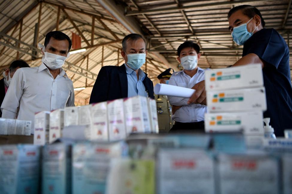 Des représentants du gouvernement examinent des médicaments illégaux et des articles contrefaits saisis lors d'une cérémonie de destruction de 130 tonnes de produits de contrefaçon à Phnom Penh, le 4 juin 2020.