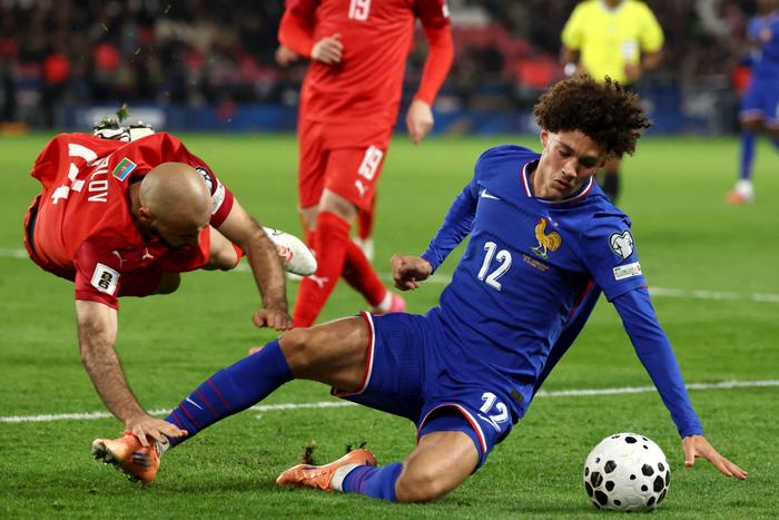 L’attaquant français n°12 Maghnes Akliouche (à droite) et le défenseur azéri n°14 Elvin Badalov (à gauche) chutent au sol en se disputant le ballon lors du match de qualification européenne du groupe D pour la Coupe du monde 2026 entre la France et l’Azerbaïdjan, au stade du Parc des Princes à Paris, le 10 octobre 2025.