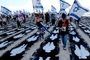 Des personnes portant des drapeaux israéliens traversent une installation commémorative aménagée sur la plage de Tel-Aviv pour marquer le troisième anniversaire de l'attaque du Hamas contre Israël du 7 octobre, le 7 octobre 2026.