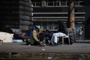Des migrants sont assis dans un campement provisoire situé sous une section aérienne de la ligne 2 du métro, dans le quartier de Stalingrad à Paris, le 27 avril 2026.