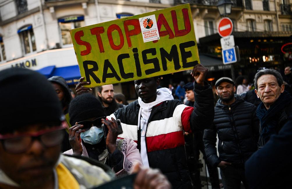 Un homme brandit une pancarte lors d'une manifestation contre le racisme organisée par des associations, des syndicats et des partis, à Paris.
