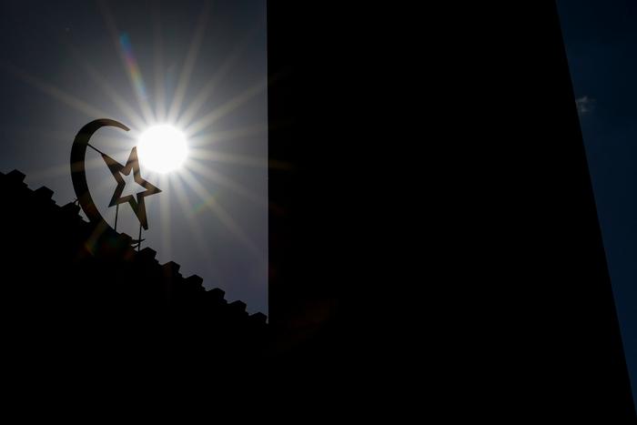 La lumière du soleil de fin de matinée découpe la silhouette de l'étoile et du croissant qui ornent l'entrée de la Grande Mosquée de Paris à Paris, le 9 septembre 2025.
