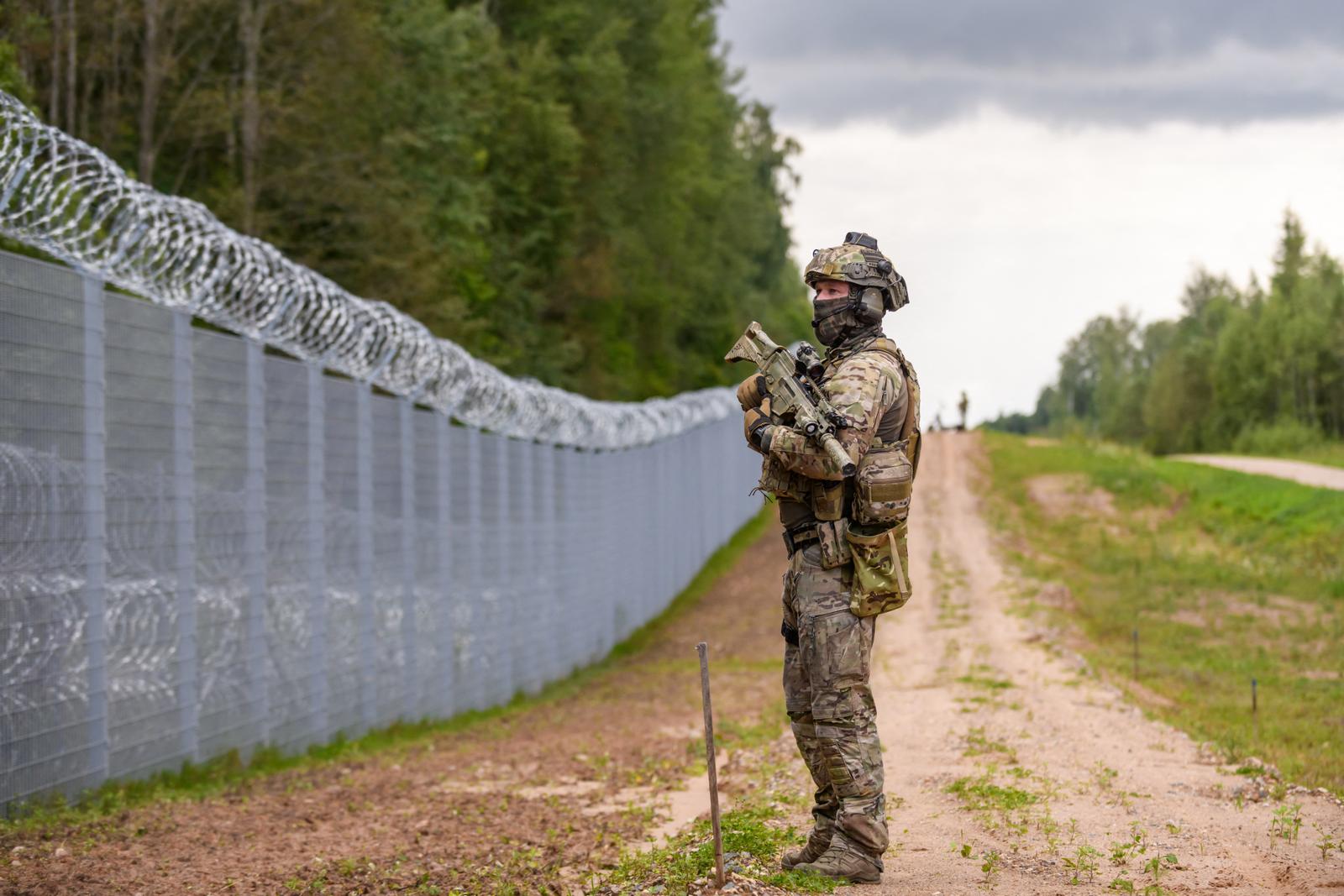 Un membre des gardes-frontières de l'État (SBG) patrouille le long d'une clôture à la frontière entre la Lettonie et le Bélarus, près de Krivanda, dans l'est de la Lettonie, le 8 août 2023, lors d'une visite du président letton.