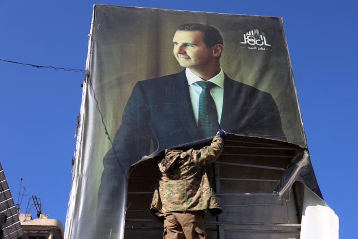 Un rebelle détruit un portrait du président syrien Bachar al-Assad à Alep, après l'entrée des djihadistes et de leurs alliés dans la ville du nord de la Syrie, le 30 novembre 2024.